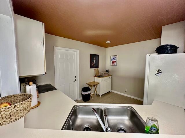 kitchen featuring white refrigerator, sink, and white cabinets