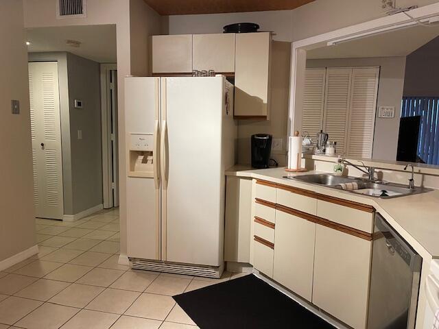 kitchen featuring stainless steel dishwasher, white refrigerator with ice dispenser, sink, and white cabinets