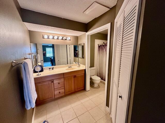 bathroom with tile patterned floors, vanity, toilet, and a textured ceiling