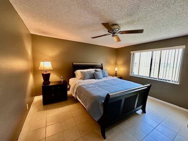 bedroom with light tile patterned floors, a textured ceiling, and ceiling fan