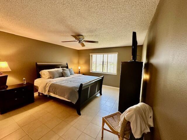 bedroom with ceiling fan, a textured ceiling, and light tile patterned floors