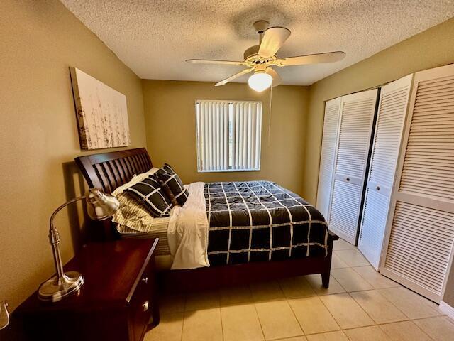 tiled bedroom with a textured ceiling, ceiling fan, and a closet