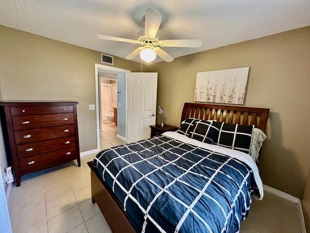 bedroom featuring ceiling fan, a textured ceiling, and light tile patterned flooring