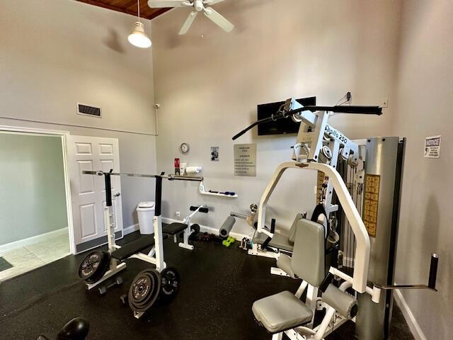 workout room featuring ceiling fan and a towering ceiling