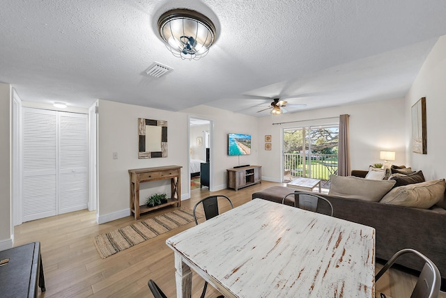 dining room with ceiling fan, a textured ceiling, and light wood-type flooring