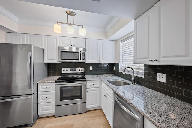 kitchen featuring appliances with stainless steel finishes, white cabinetry, sink, hanging light fixtures, and crown molding