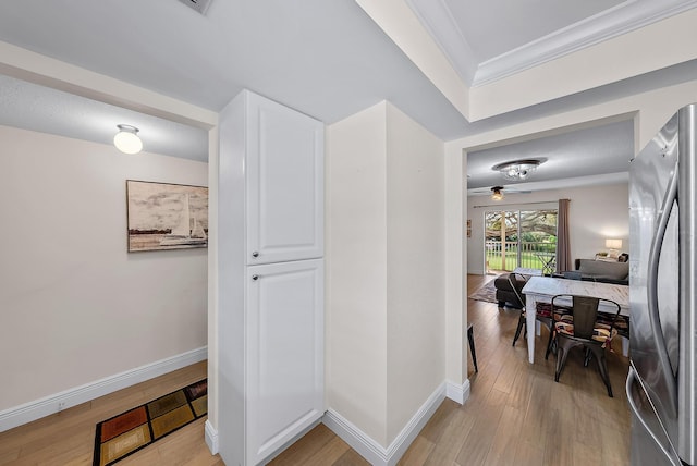 corridor with ornamental molding and light hardwood / wood-style floors