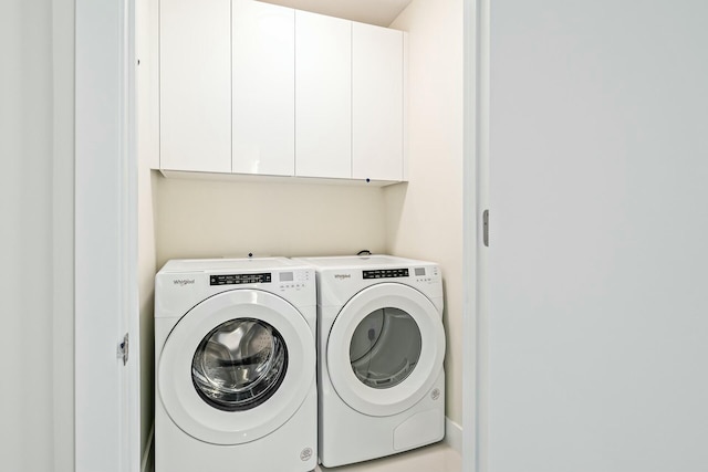 clothes washing area with cabinets and washing machine and clothes dryer