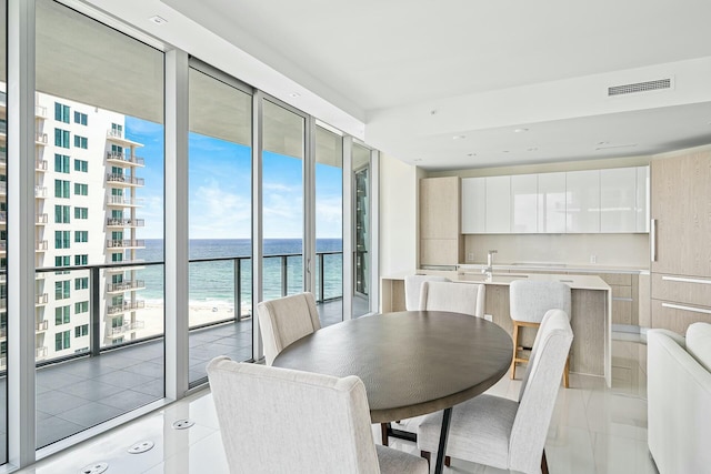 dining space featuring light tile patterned floors, floor to ceiling windows, and a water view