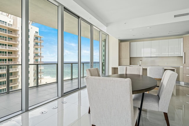 tiled dining room featuring floor to ceiling windows and a water view