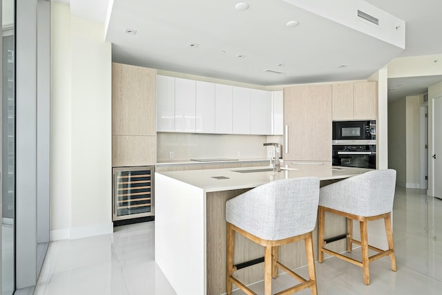 kitchen featuring built in microwave, sink, wine cooler, wall oven, and a center island with sink