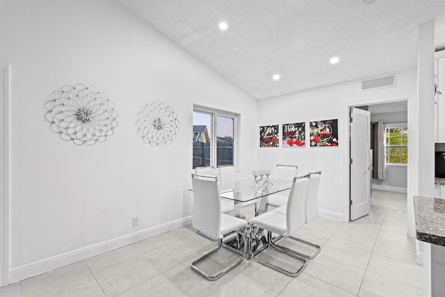 tiled dining space with vaulted ceiling and a textured ceiling