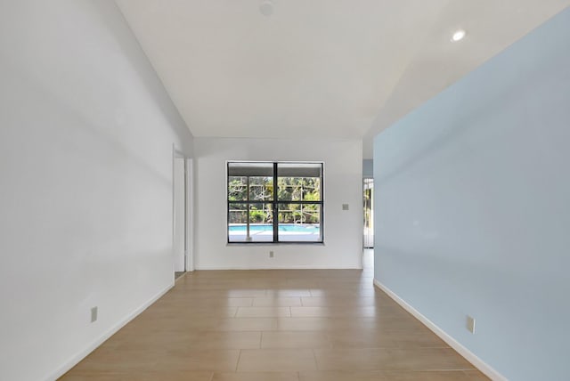 spare room featuring lofted ceiling and light wood-type flooring