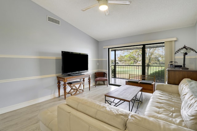 living room featuring vaulted ceiling, a textured ceiling, ceiling fan, and light hardwood / wood-style flooring