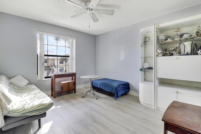 bedroom with ceiling fan, light hardwood / wood-style floors, and a textured ceiling