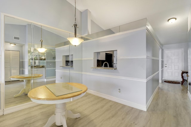 dining space with hardwood / wood-style floors, high vaulted ceiling, and sink