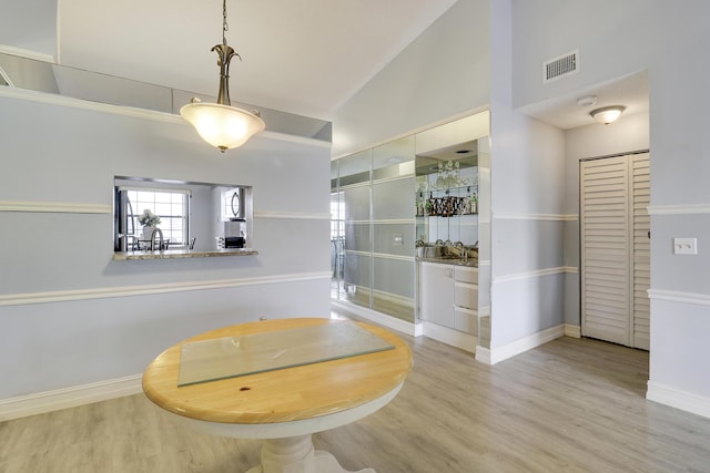 dining room with high vaulted ceiling and light wood-type flooring