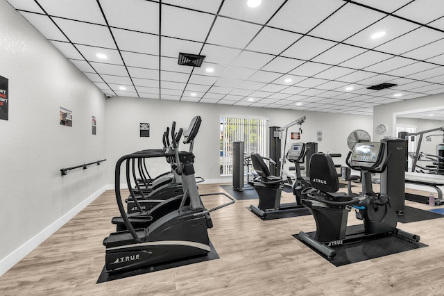 gym featuring a paneled ceiling and light hardwood / wood-style floors