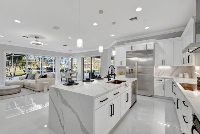 kitchen with appliances with stainless steel finishes, light stone counters, pendant lighting, white cabinetry, and a kitchen island with sink