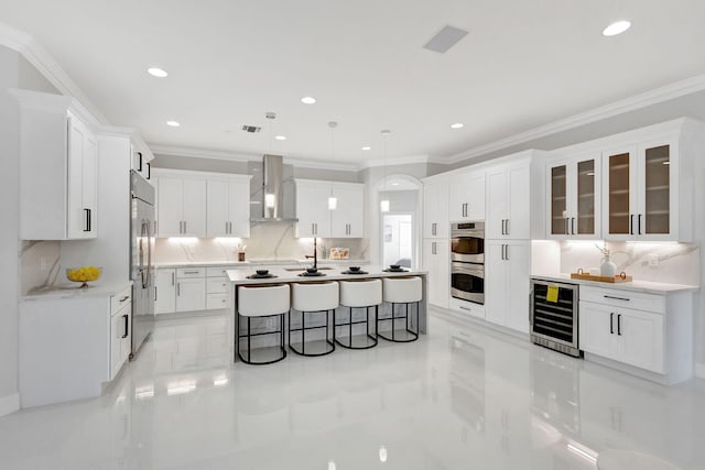 kitchen featuring beverage cooler, white cabinetry, wall chimney exhaust hood, and pendant lighting