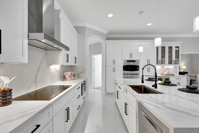 kitchen with wall chimney range hood, appliances with stainless steel finishes, white cabinets, and decorative light fixtures