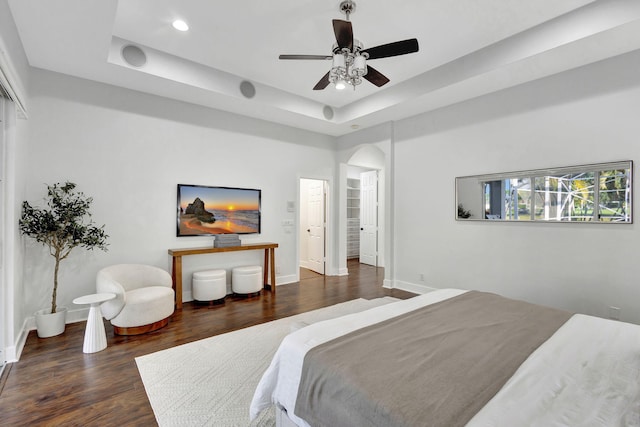 bedroom featuring a raised ceiling, ceiling fan, and dark wood-type flooring