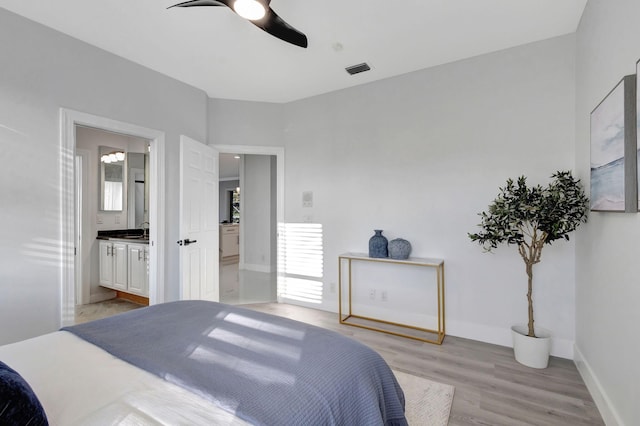 bedroom with multiple windows, ceiling fan, connected bathroom, and light hardwood / wood-style floors