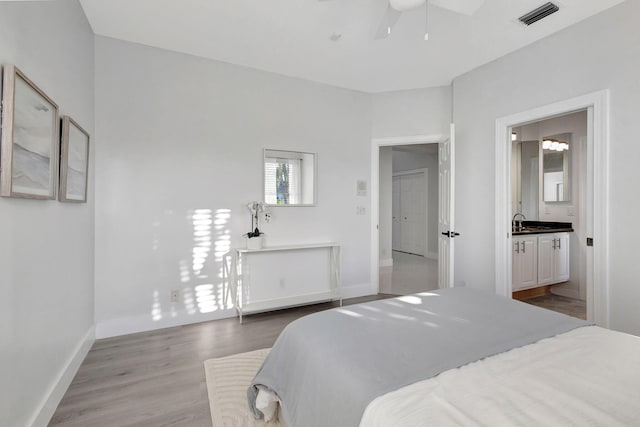 bedroom featuring connected bathroom, light hardwood / wood-style flooring, and sink