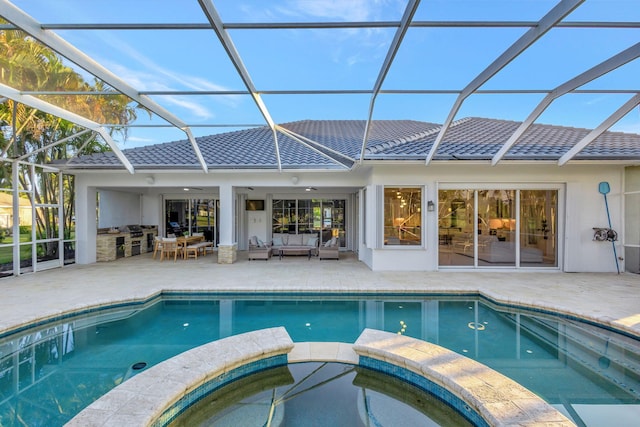 view of swimming pool with a lanai, a patio, an in ground hot tub, and exterior kitchen