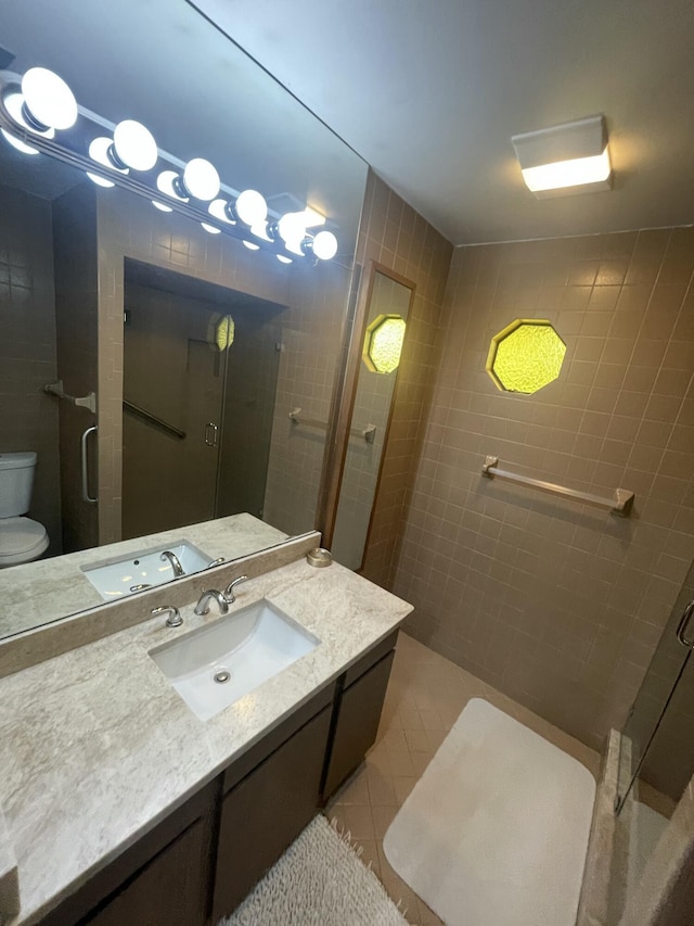 bathroom with vanity, a shower with shower door, tile patterned floors, and toilet