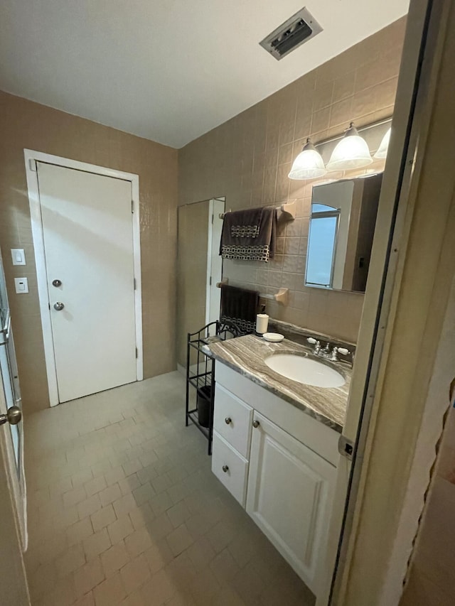 bathroom featuring decorative backsplash, vanity, and tile walls