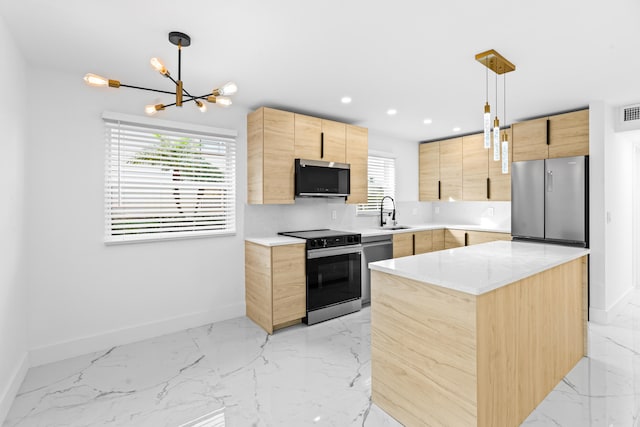 kitchen featuring light brown cabinetry, decorative light fixtures, a center island, stainless steel appliances, and light stone countertops