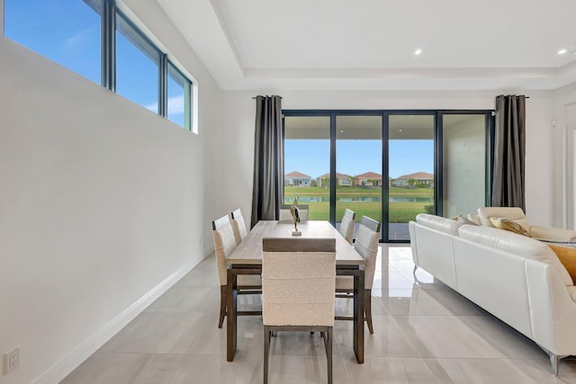 tiled dining room with a tray ceiling and a healthy amount of sunlight