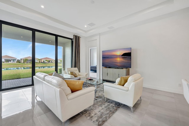 living room featuring a tray ceiling and light tile patterned flooring