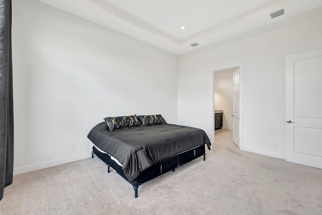 carpeted bedroom featuring connected bathroom and a tray ceiling