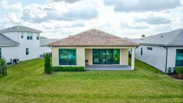 rear view of property featuring a yard, central AC unit, and a patio area