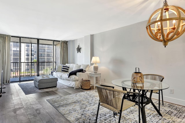 dining space featuring a notable chandelier, a wall of windows, and wood-type flooring