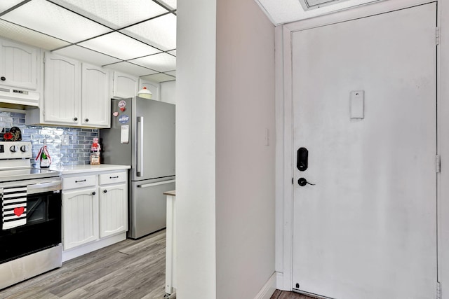 kitchen with appliances with stainless steel finishes, white cabinetry, backsplash, light hardwood / wood-style floors, and a drop ceiling