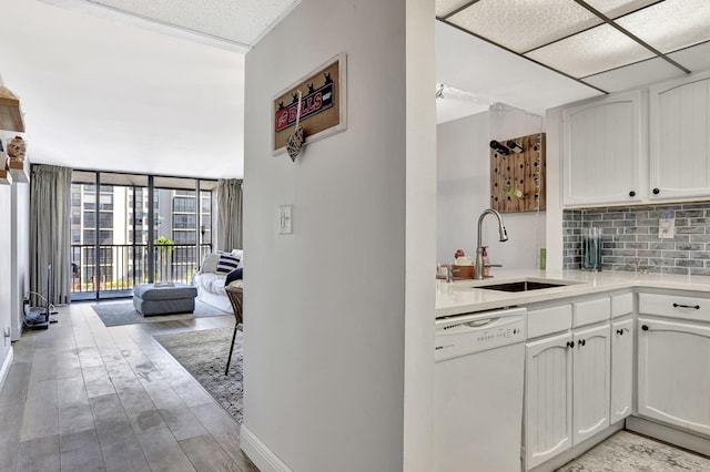 kitchen with white cabinetry, a wall of windows, dishwasher, and sink