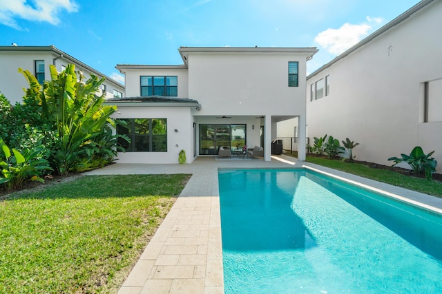 back of property with ceiling fan, outdoor lounge area, a patio, and a lawn