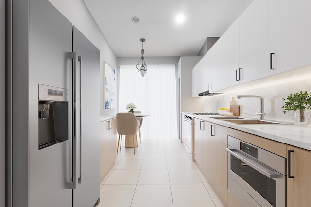 kitchen featuring light tile patterned flooring, pendant lighting, white cabinets, stainless steel appliances, and light stone countertops