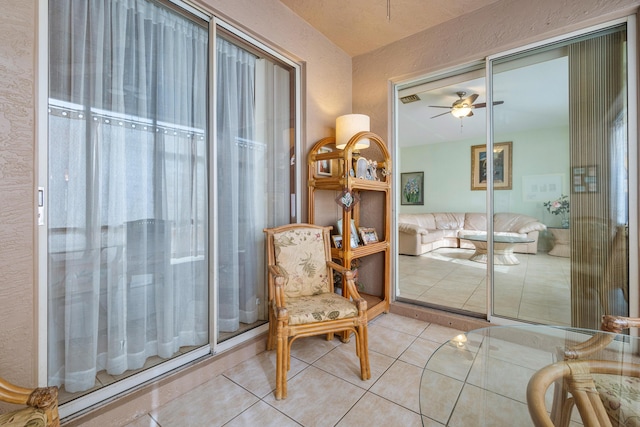 living area featuring light tile patterned floors and ceiling fan