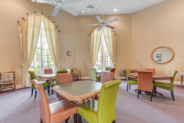 carpeted dining space featuring a towering ceiling and ceiling fan