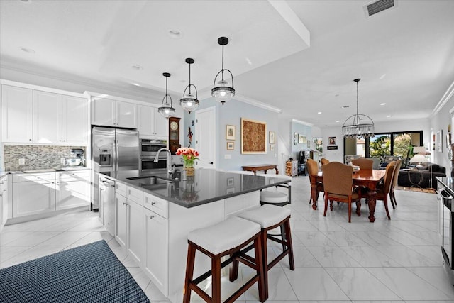 kitchen featuring white cabinetry, sink, decorative light fixtures, and a kitchen island with sink