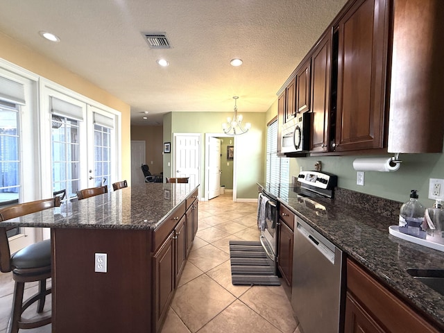 kitchen featuring visible vents, plenty of natural light, french doors, appliances with stainless steel finishes, and a kitchen breakfast bar