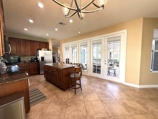 kitchen featuring a kitchen bar, visible vents, a kitchen island, french doors, and stainless steel fridge with ice dispenser