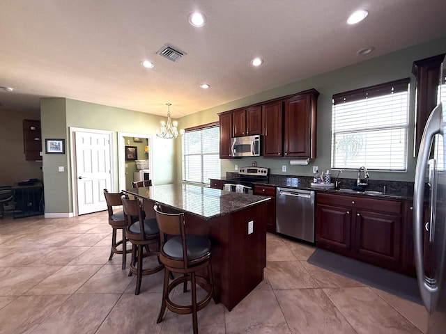 kitchen with a breakfast bar area, visible vents, a sink, appliances with stainless steel finishes, and a center island