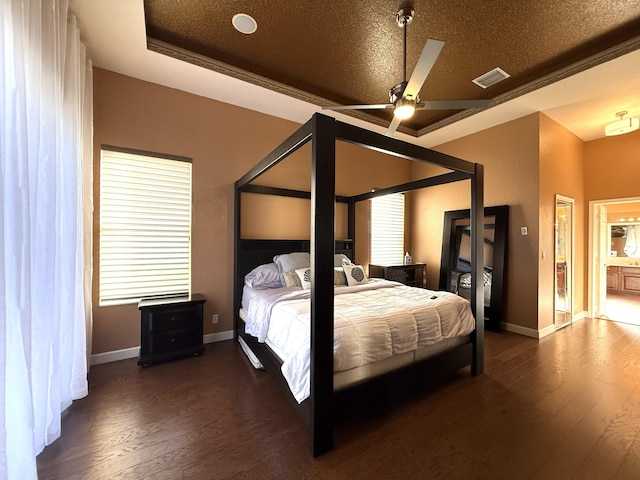 bedroom featuring a raised ceiling, dark wood-style floors, visible vents, and a textured ceiling