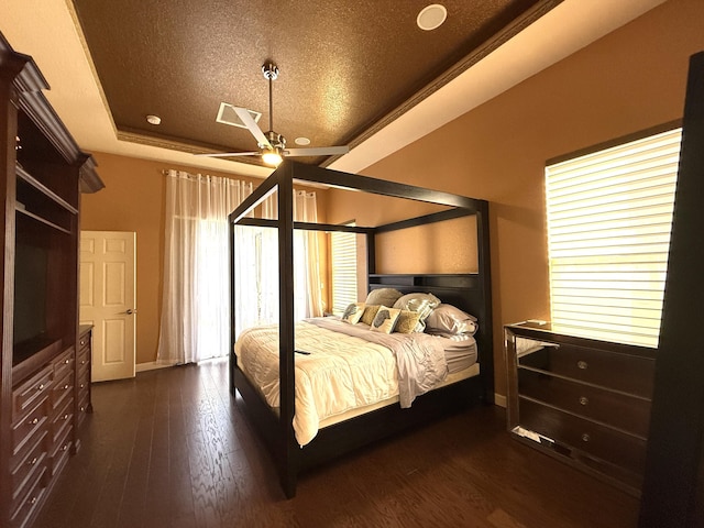 bedroom with a ceiling fan, a tray ceiling, a textured ceiling, baseboards, and dark wood-style flooring