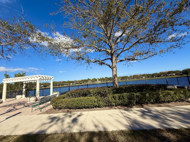 view of community featuring a pergola, fence, and a water view